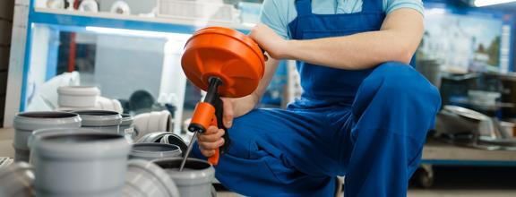 Kneeling man wearing overalls mixing construction materials in bucket