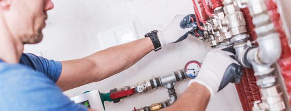 Gloved plumber adjusts pipes