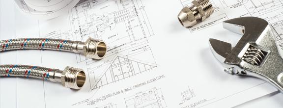 Wrench and plumbing items laying on top of a blueprint